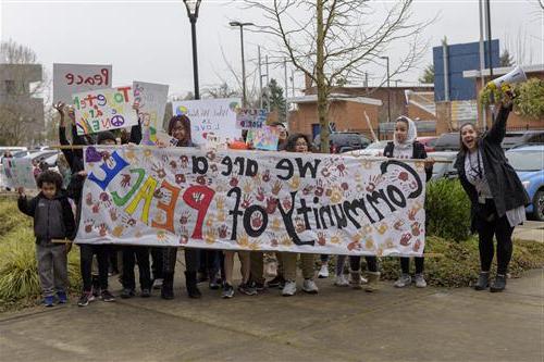 Faubion and Concordia community members lead the Peach March with a large banner that reads "We are a community of Peace" 